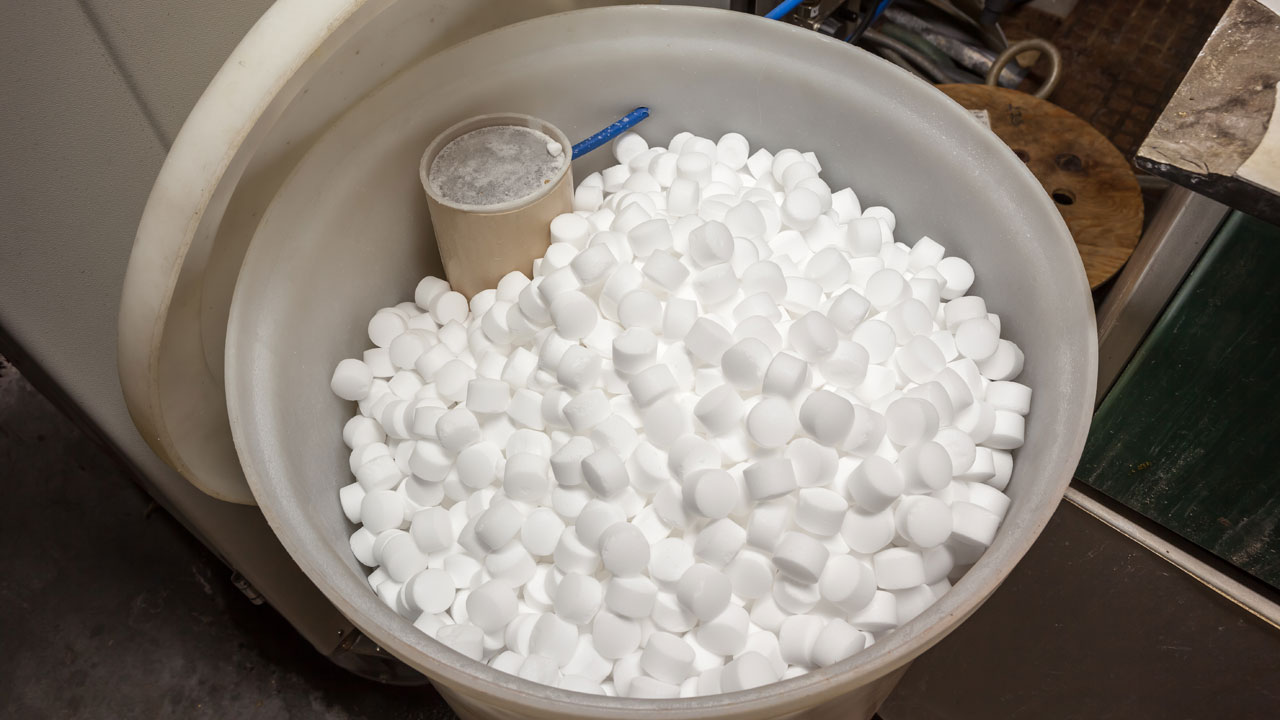 Lid removed from brine tank of home water softener showing salt pellets