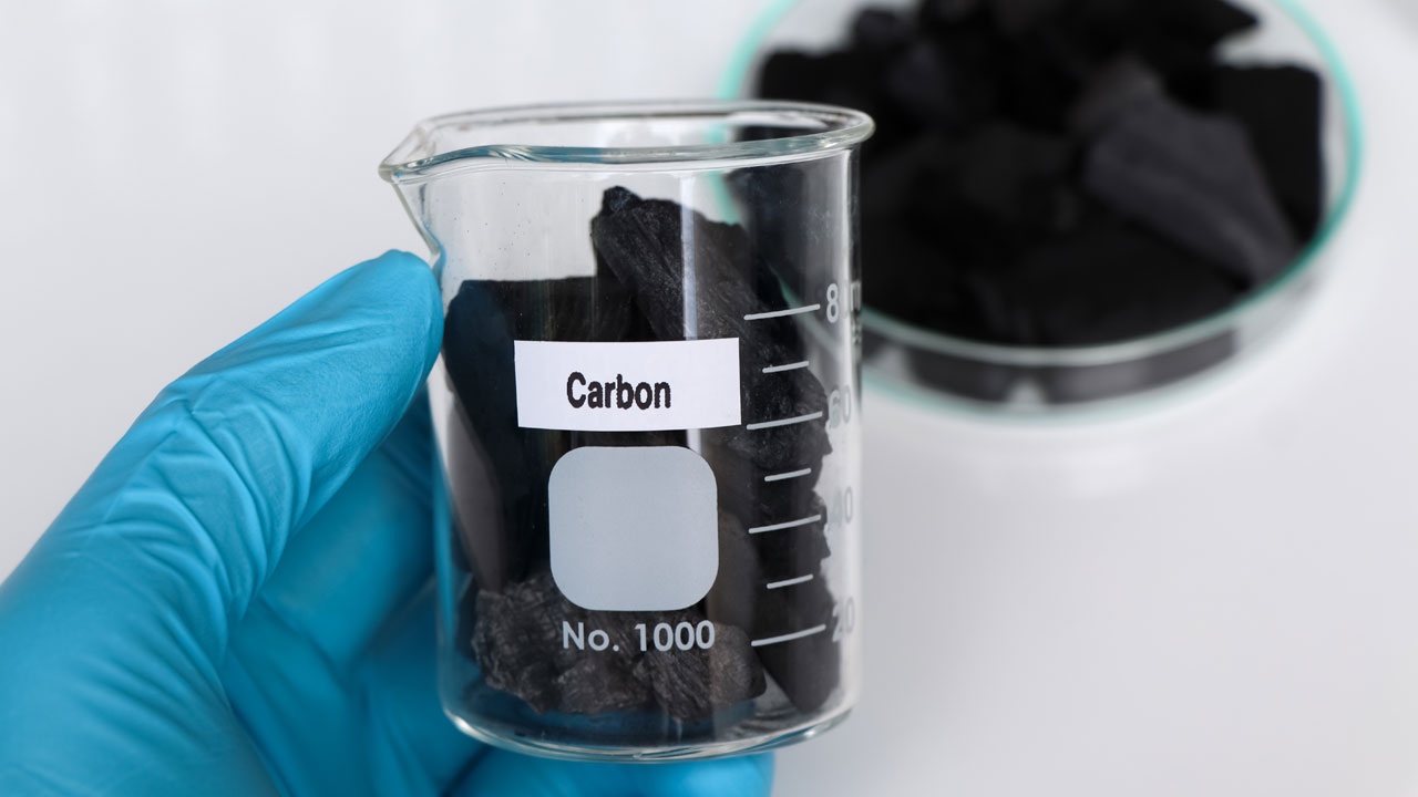 Carbon in a beaker labeled "carbon" part of a process of manufacturing and testing carbon
