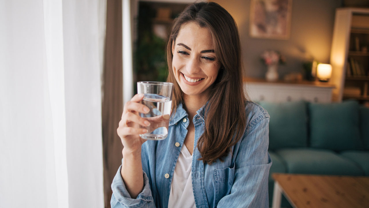 Woman smiling drinking clean filtered water from a glass