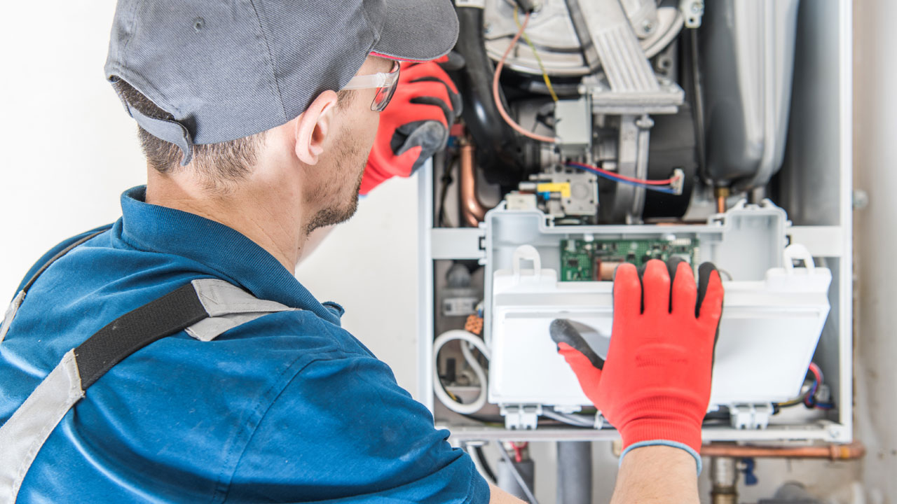 Technician at open furnace inspecting parts