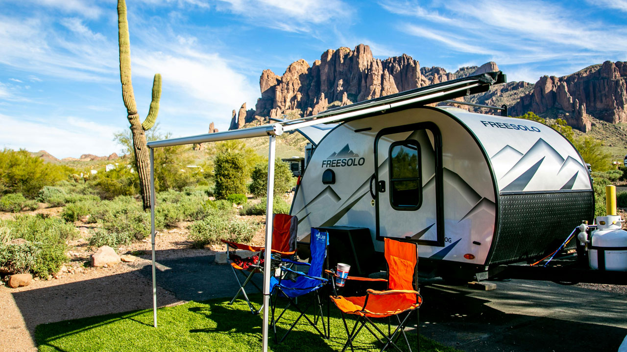 Thanks to winterizing, the small trailer RV owner set up quickly to enjoy the warm weather of summer camping in a red rock setting next to a cactus