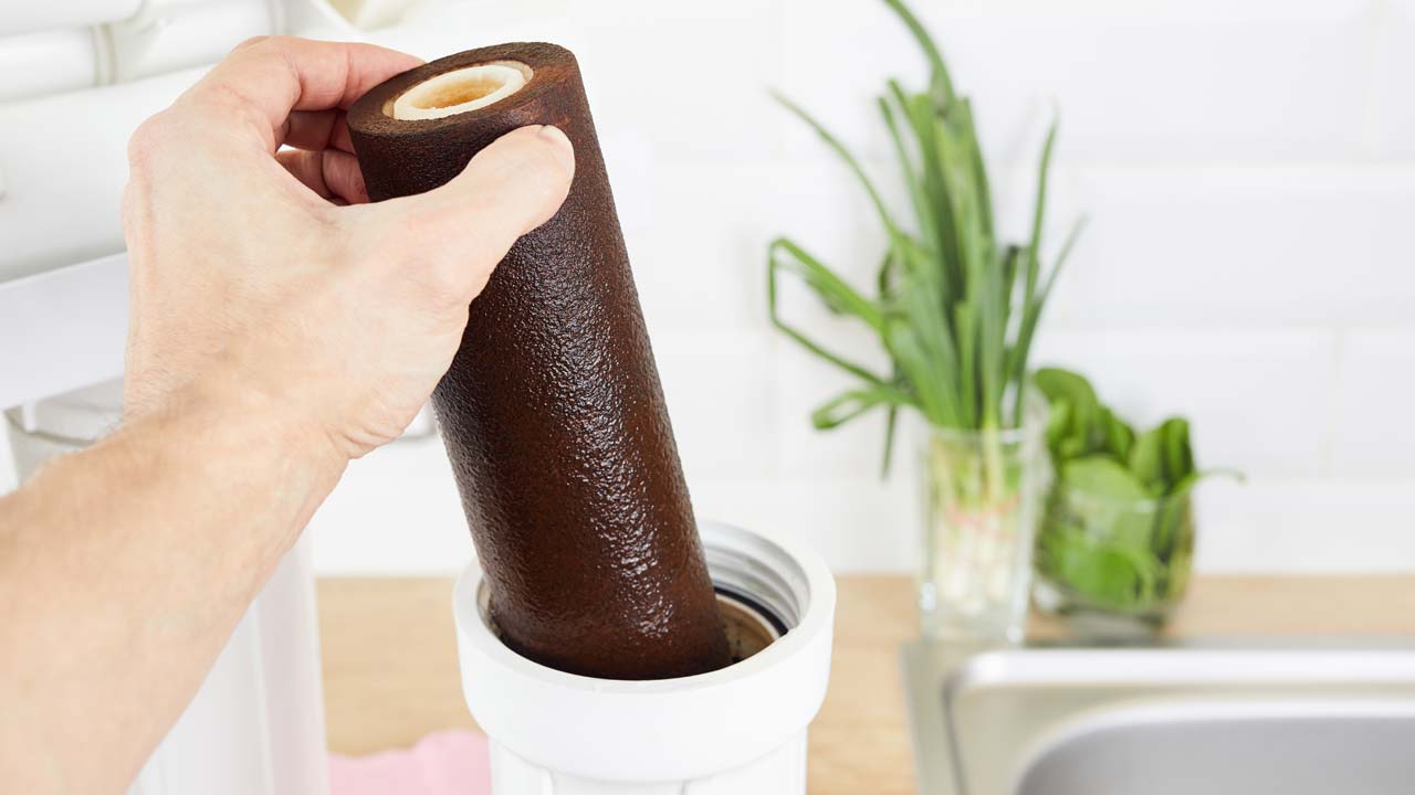 A dirty, clogged filter in white filter housing requiring replacement