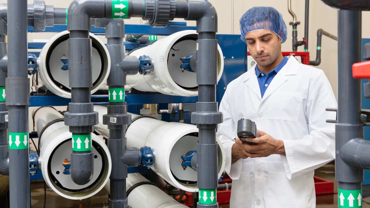 A technician or scientist at a water bottling plant checks data