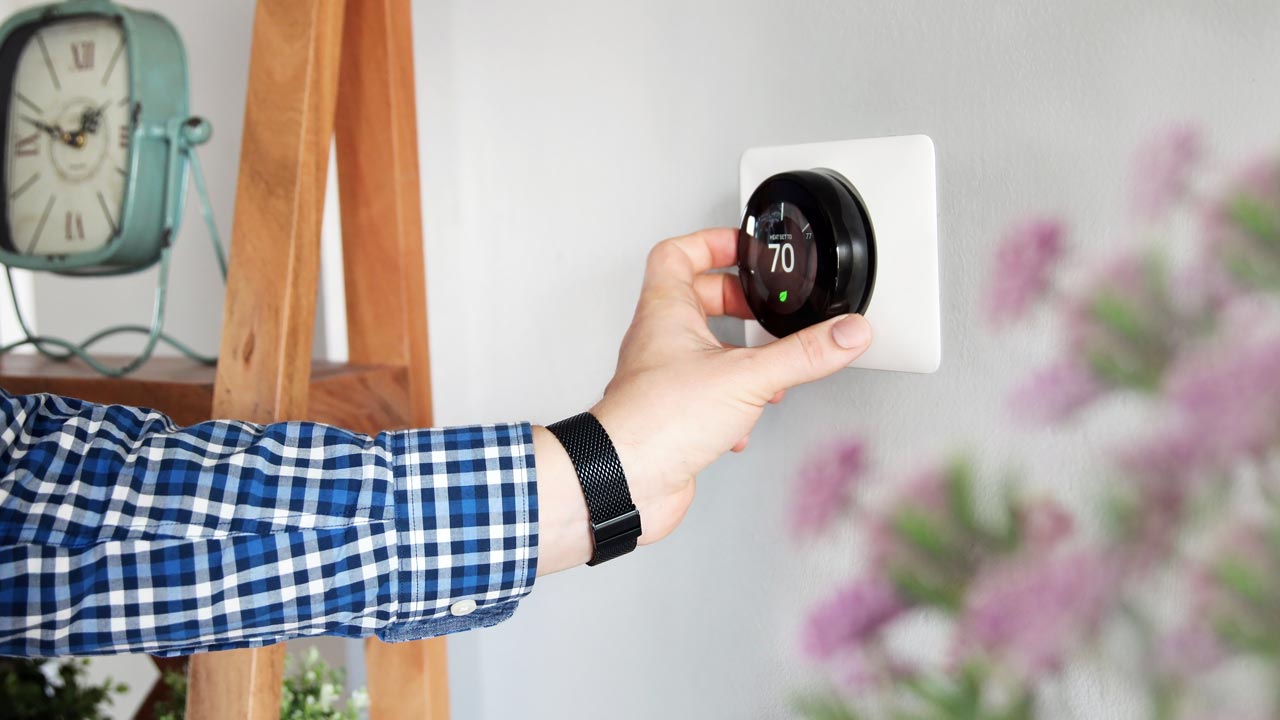 Hand adjusting a thermostat indoor comfort settings
