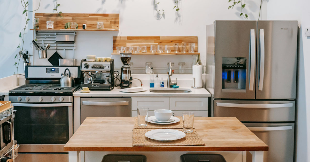 Compact kitchen with stainless steel refrigerator and water and ice dispenser next to a sink