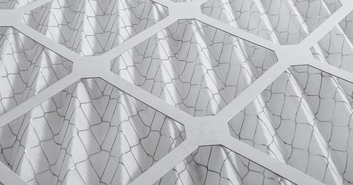 Close up of pleated HVAC air filter media with wire reinforcements and cardboard frame