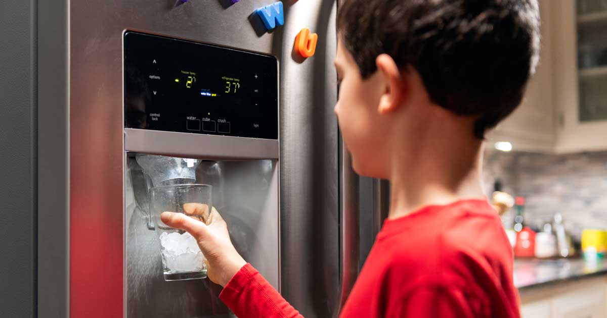 Boy a refrigerator getting water and ice from a dispenser after a refrigerator water filter